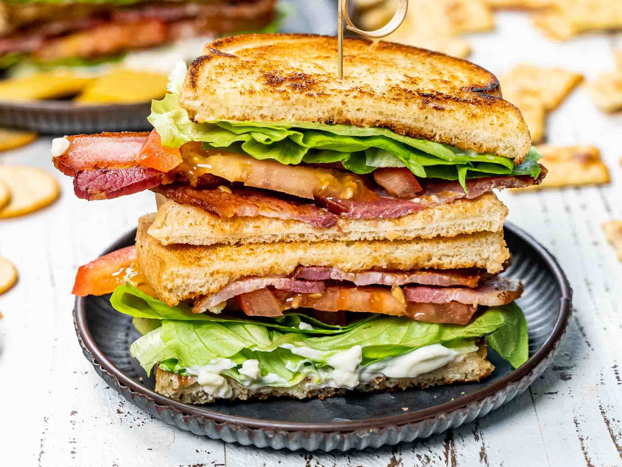 a BLT sandwich cut in half and stacked on a plate.
