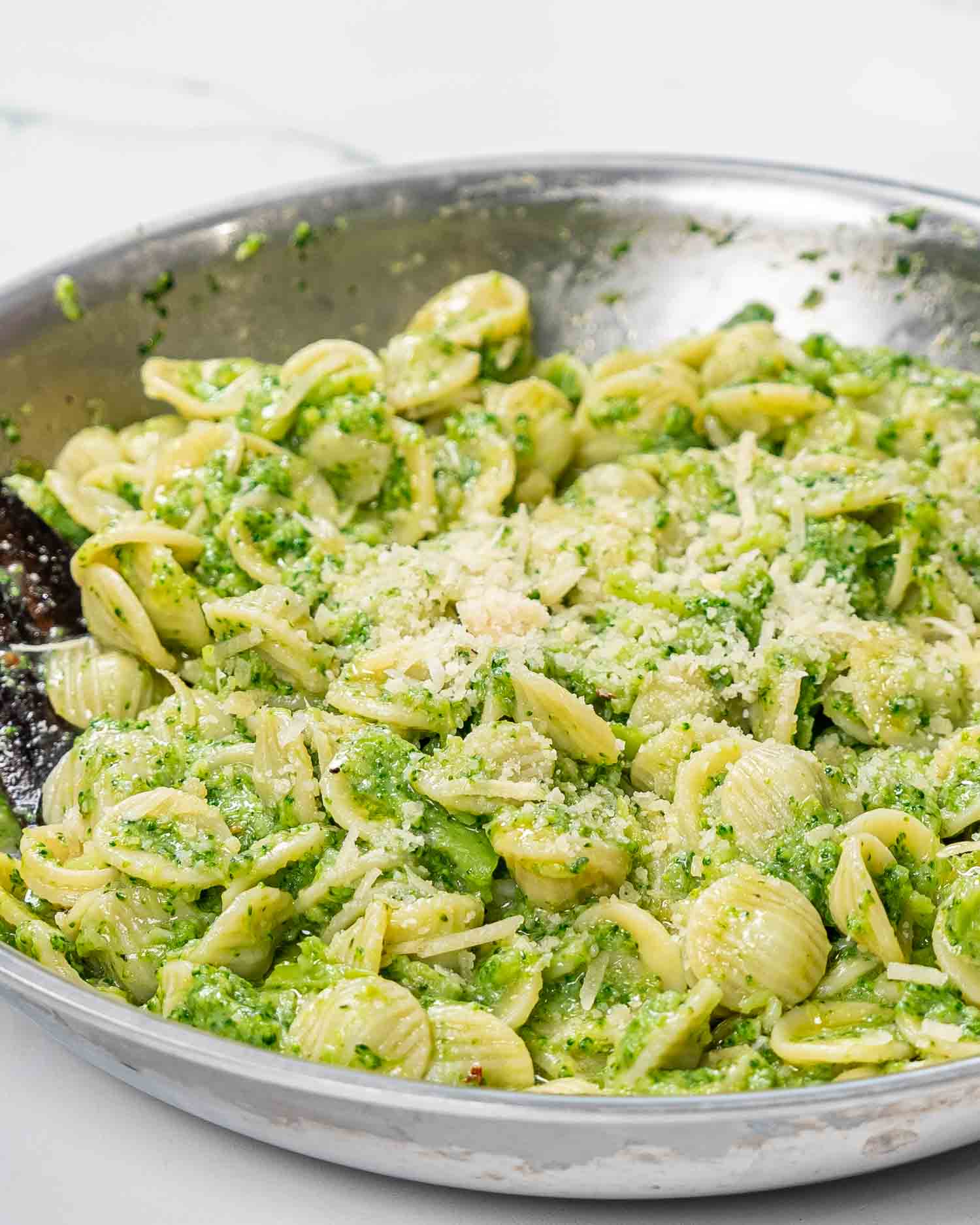 freshly made broccoli pasta with parmesan cheese in a skillet.