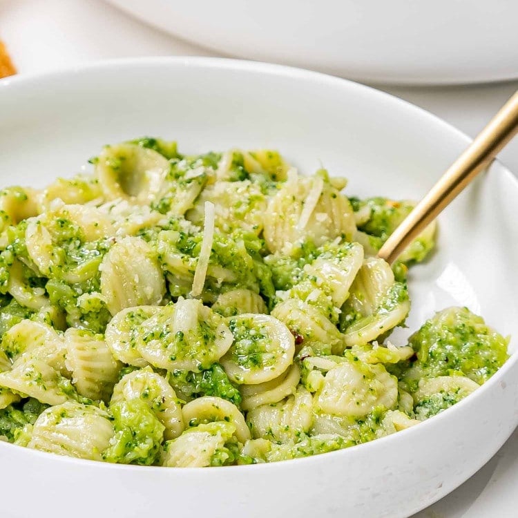 a serving of broccoli pasta in a white bowl.