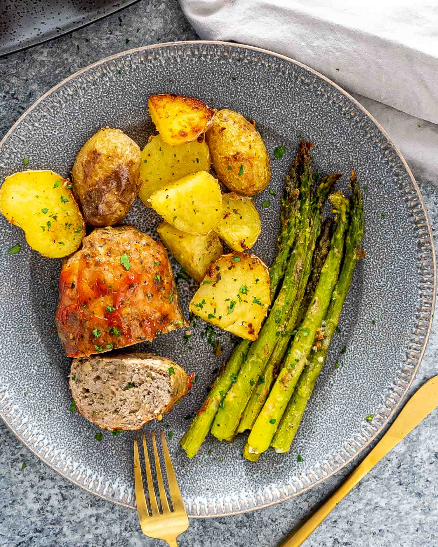 a mini turkey meatloaf on a plate with roasted potatoes and asparagus.