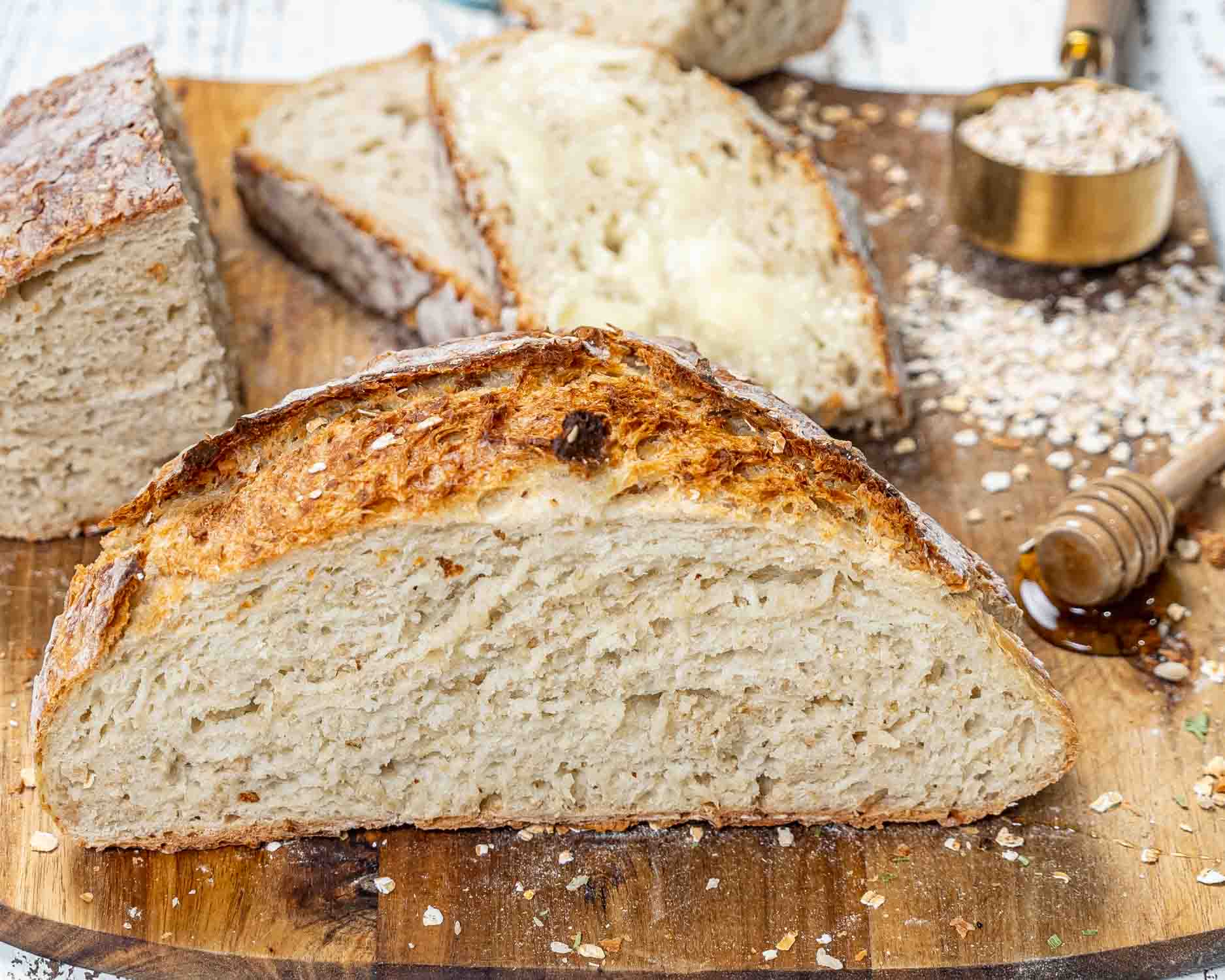 a half of no knead honey oat bread on a cutting board.