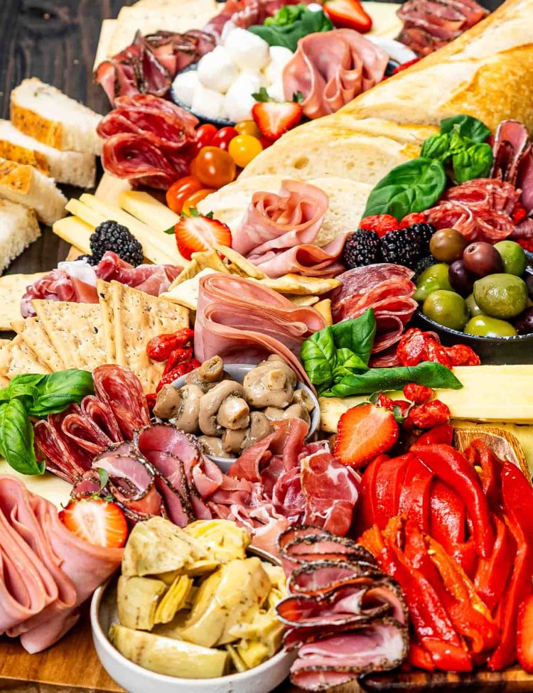 an antipasto platter loaded with salami, deli meats, mix of olives, cheeses, crackers and nuts.