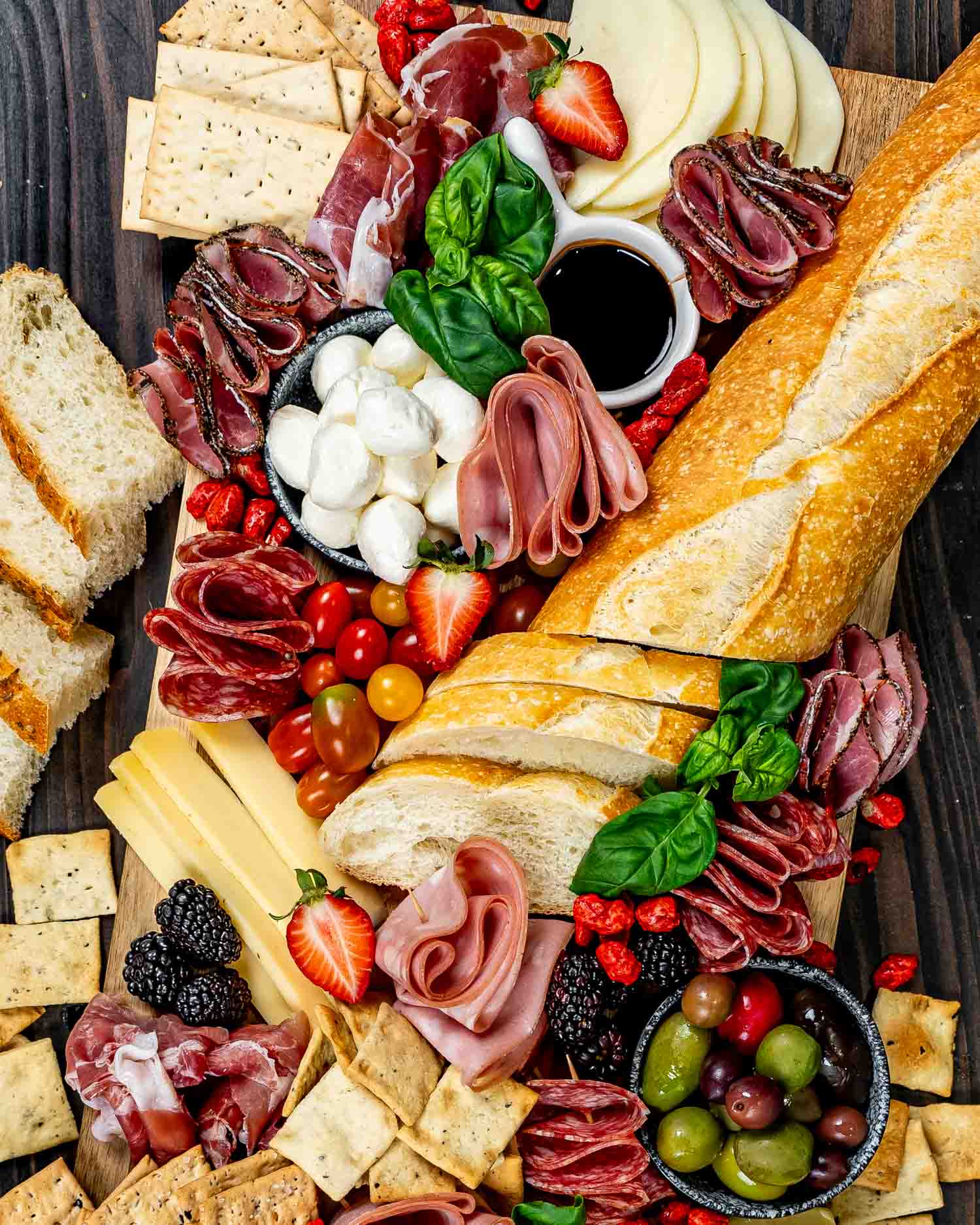 an antipasto platter loaded with salami, deli meats, mix of olives, cheeses, crackers and nuts.