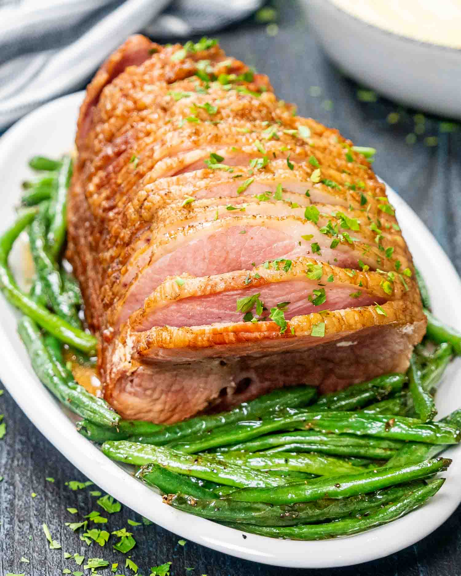 instant pot ham with green beans on a white platter.