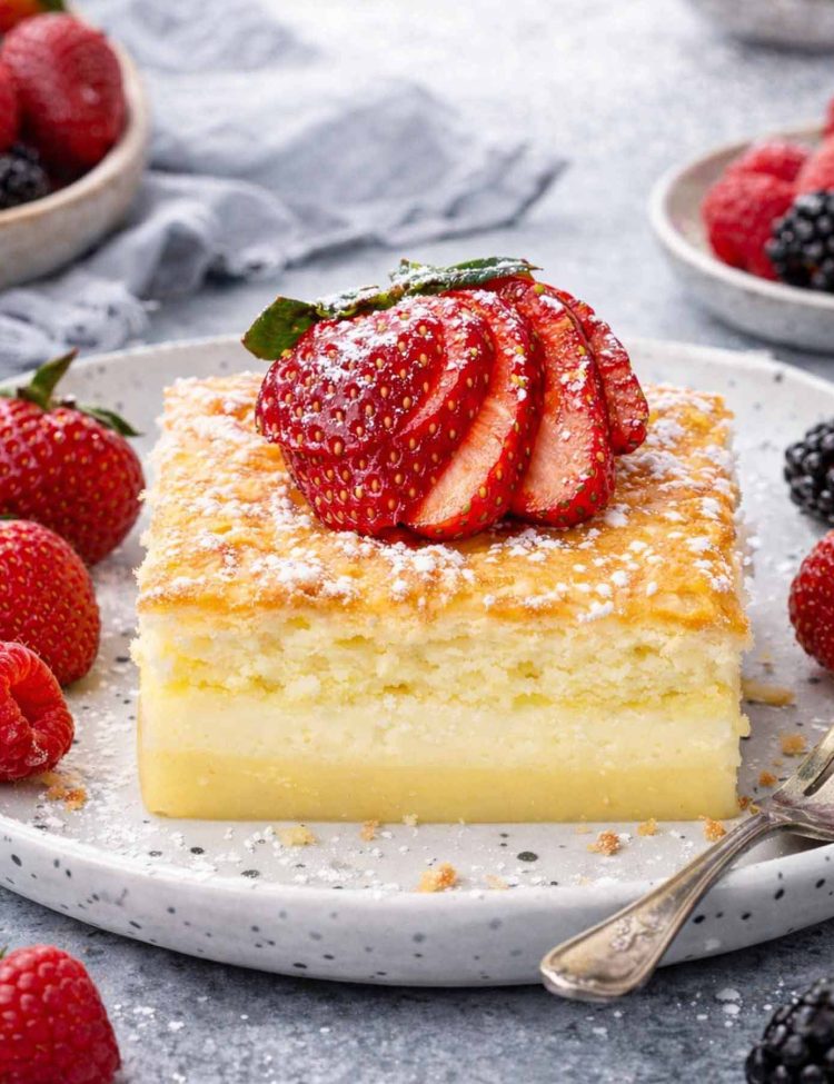 magic cake on a plate garnished with powdered sugar and a strawberry.
