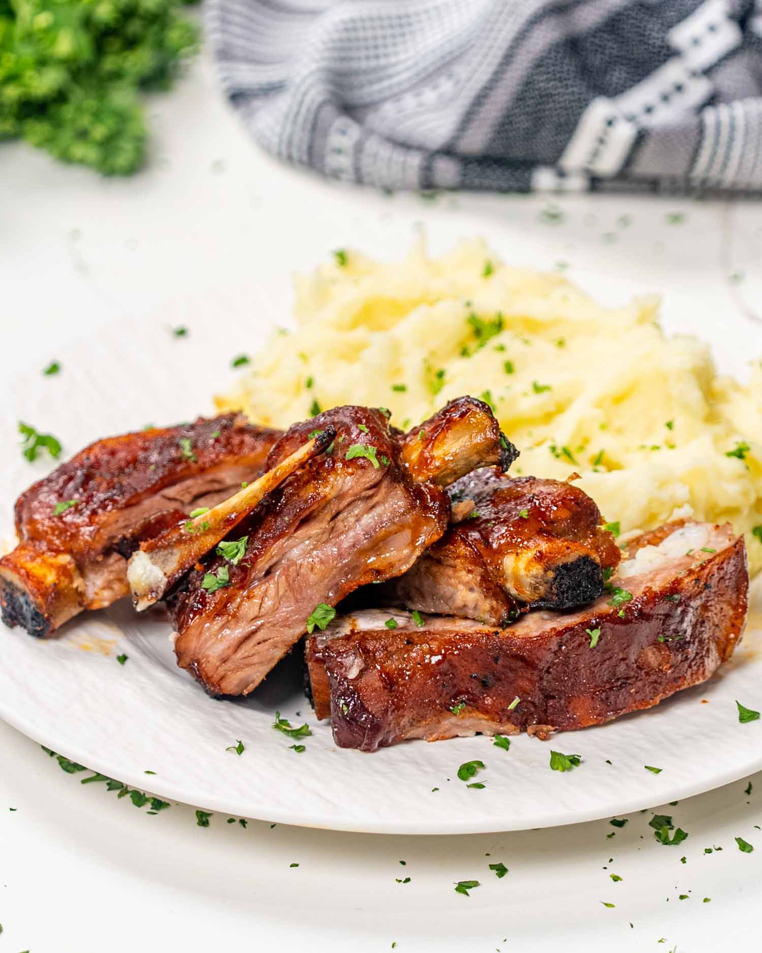 a serving of oven baked bbq ribs with mashed potatoes on a white plate.
