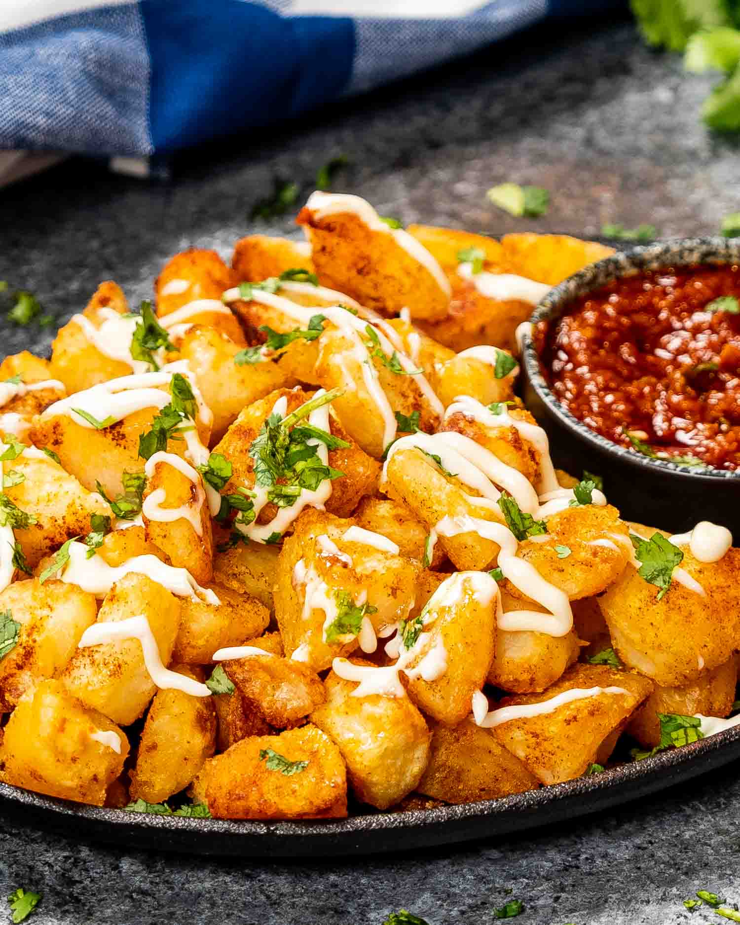 patatas bravas in an oval skillet with spicy red sauce.