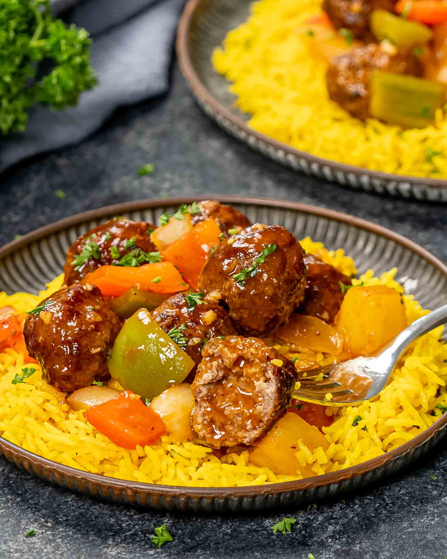 sweet and sour meatballs over a bed of yellow rice.