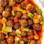 sweet and sour meatballs on a white serving platter.