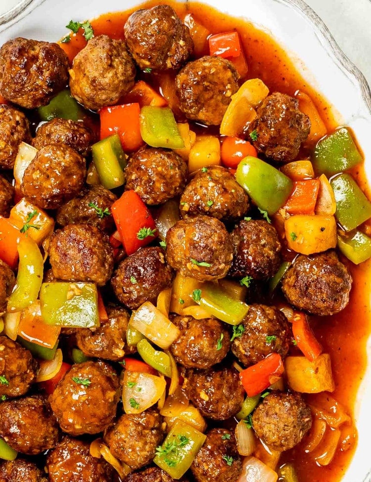 sweet and sour meatballs on a white serving platter.