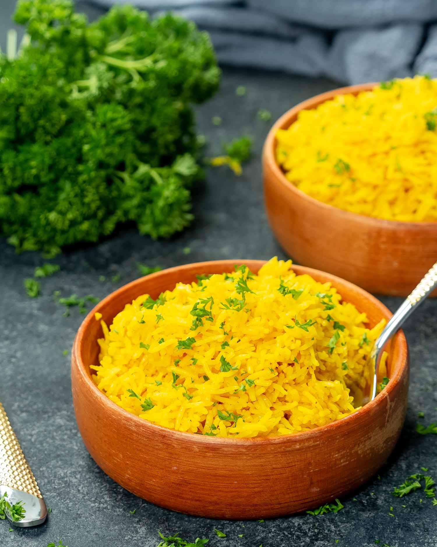 two plates with yellow rice and garnished with parsley.