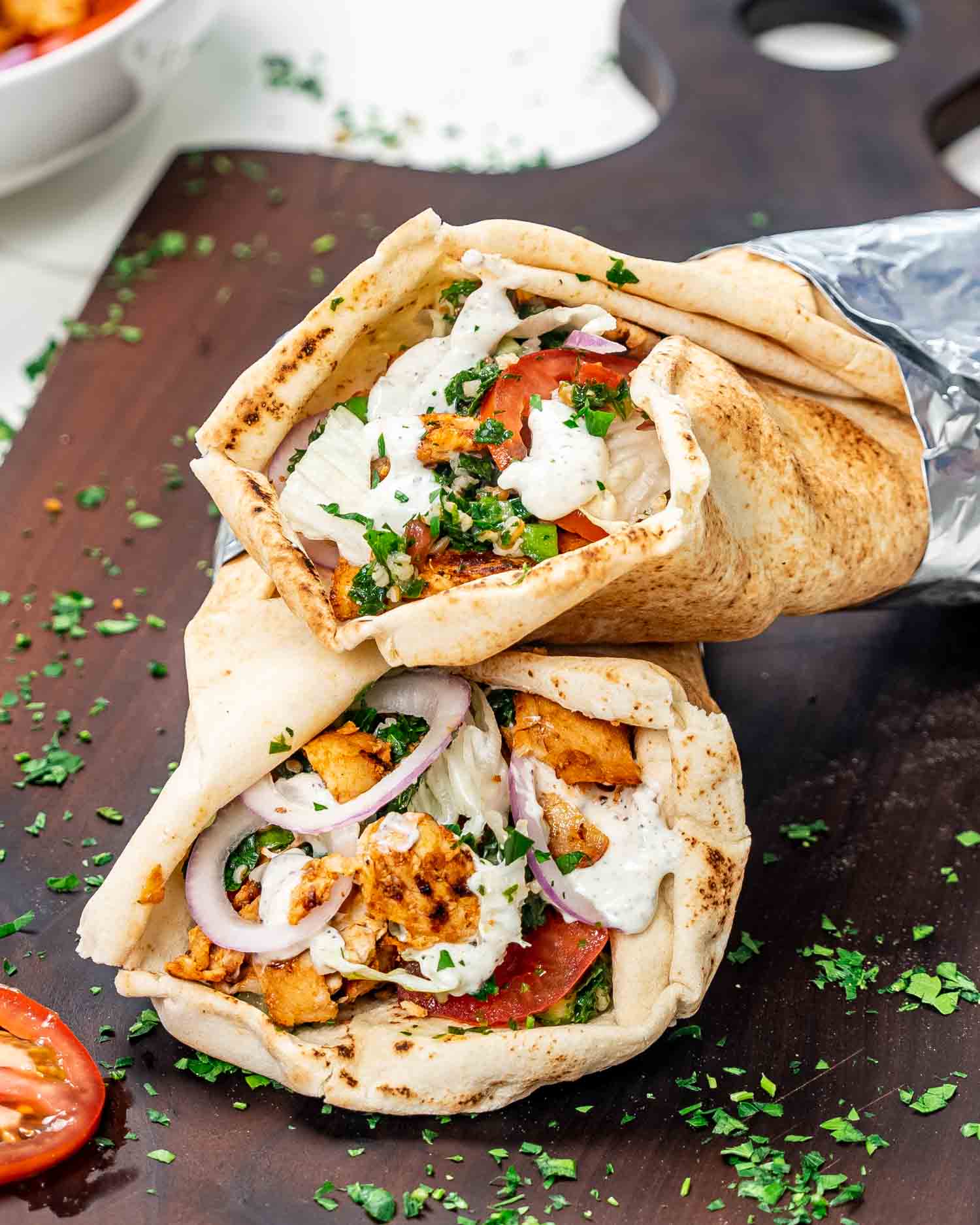 two chicken doner kebabs on a cutting board with a delicious yogurt sauce.