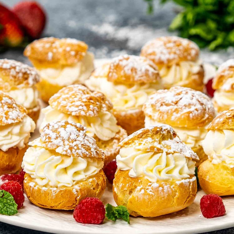 puffs (choux pastry) filled with whipped cream on a platter.