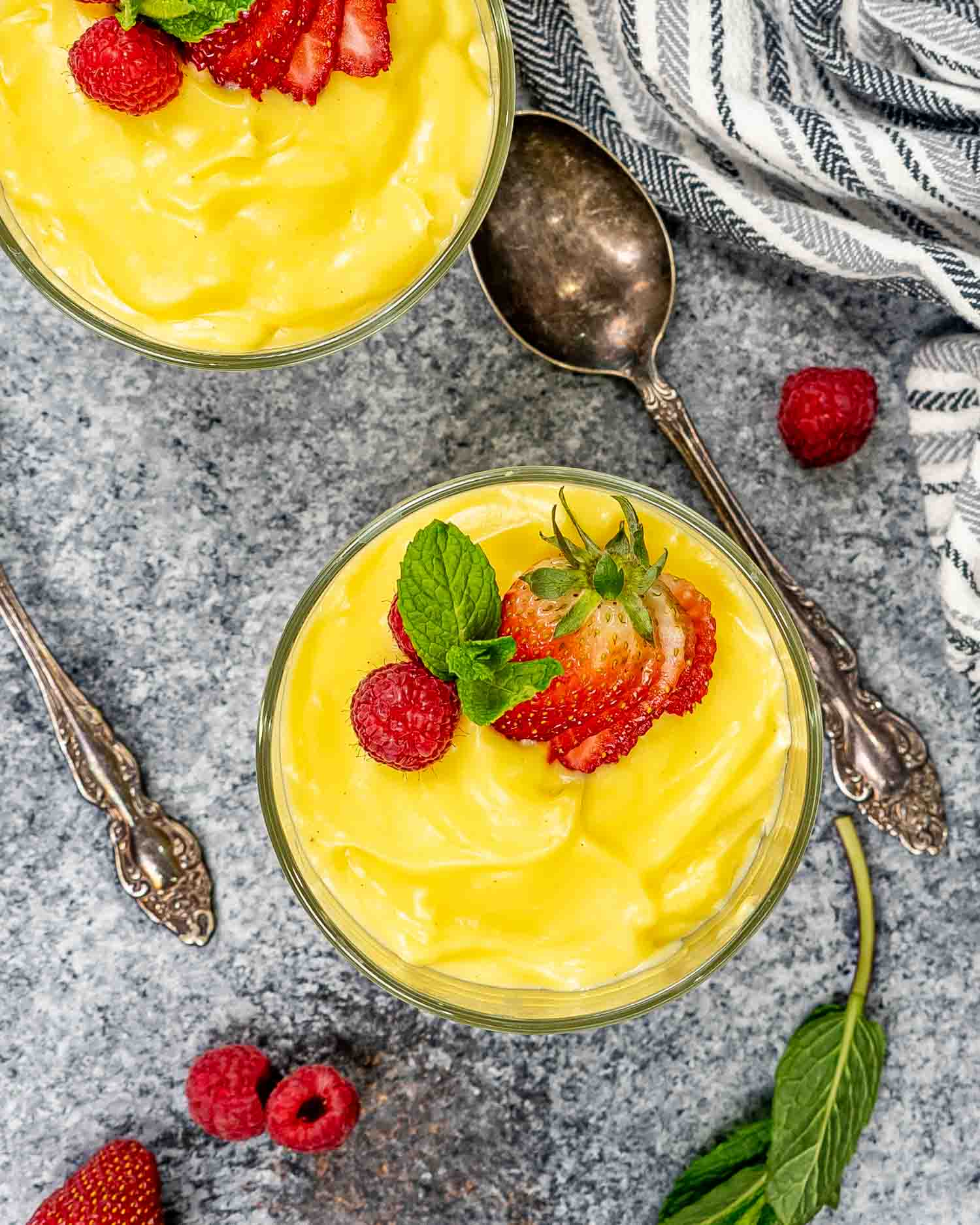 vanilla custard in two glass bowls topped with strawberries.