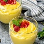vanilla custard in two glass bowls topped with strawberries.