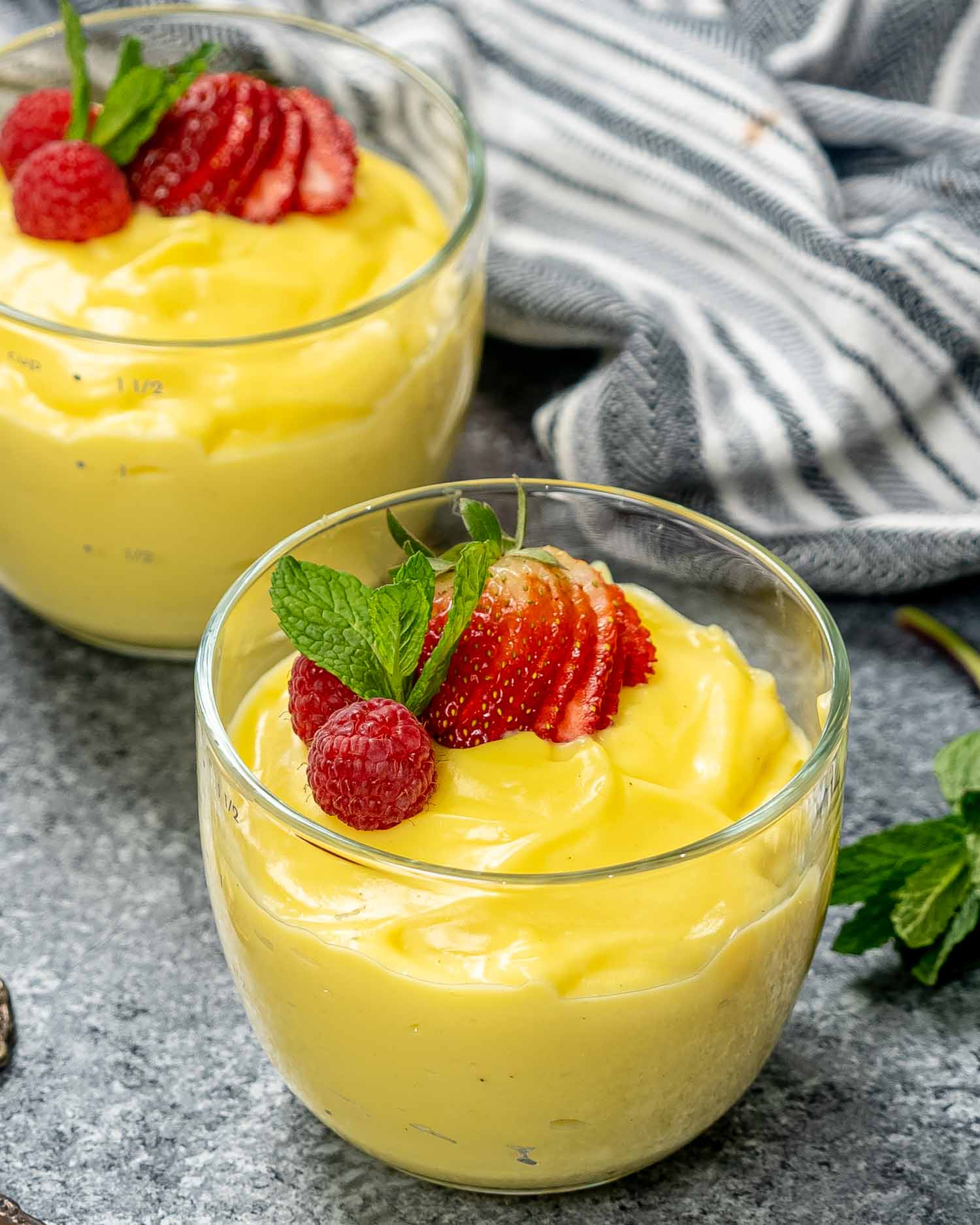 vanilla custard in two glass bowls topped with strawberries.