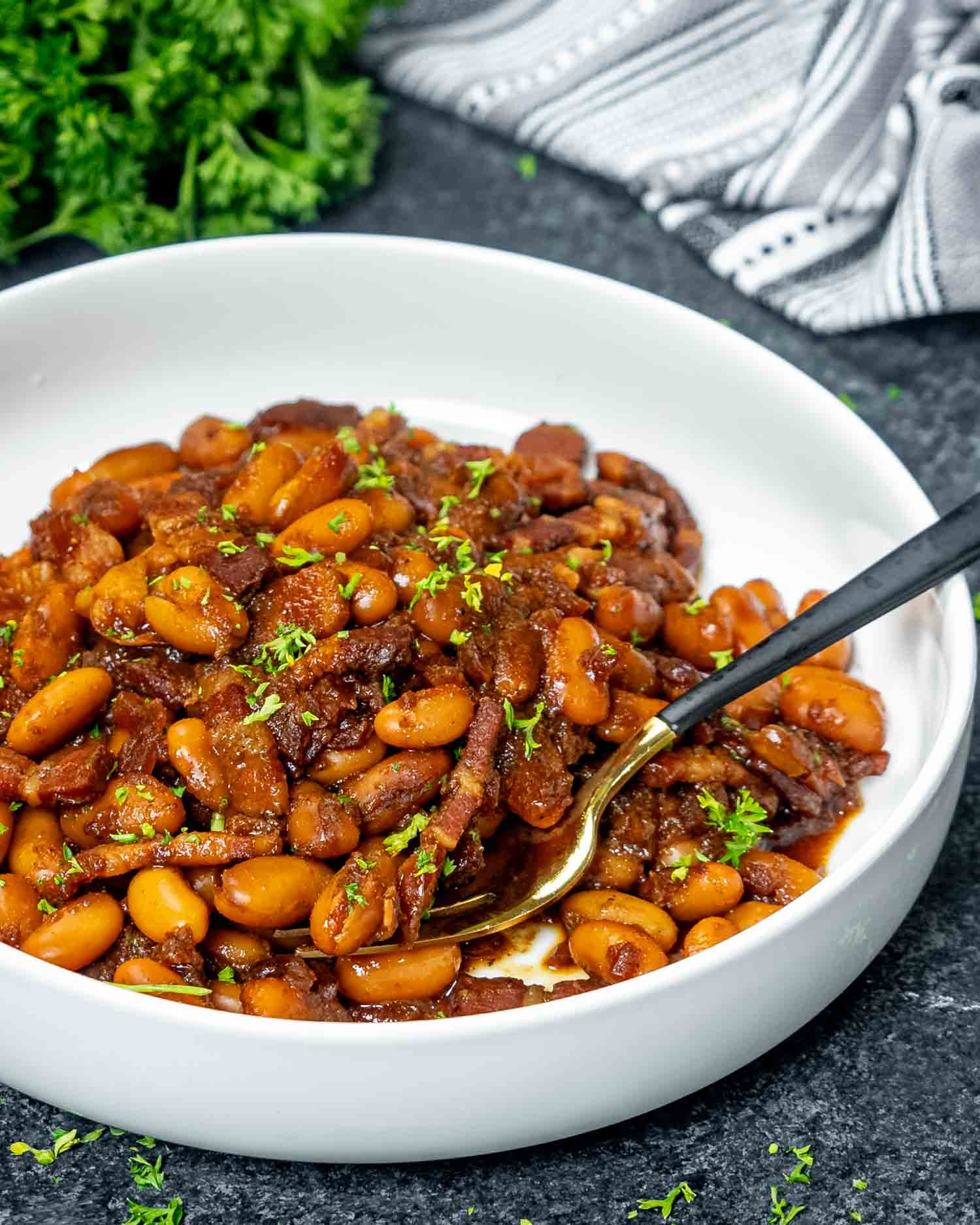 baked beans in a white bowl with a fork inside.