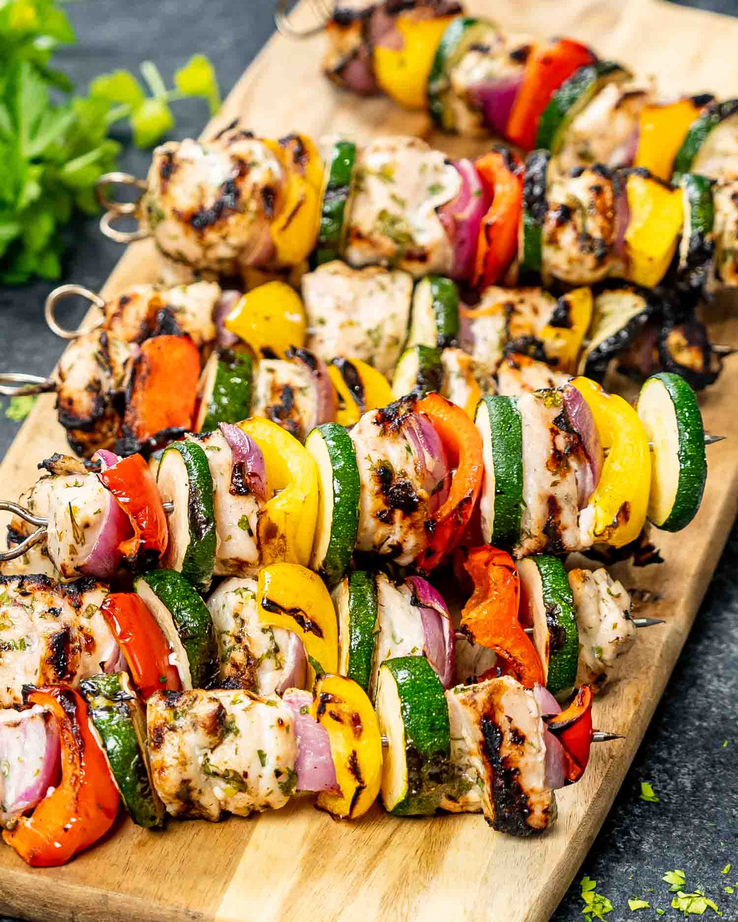 a stack of fresh off the grill grilled chicken kebabs on a cutting board.