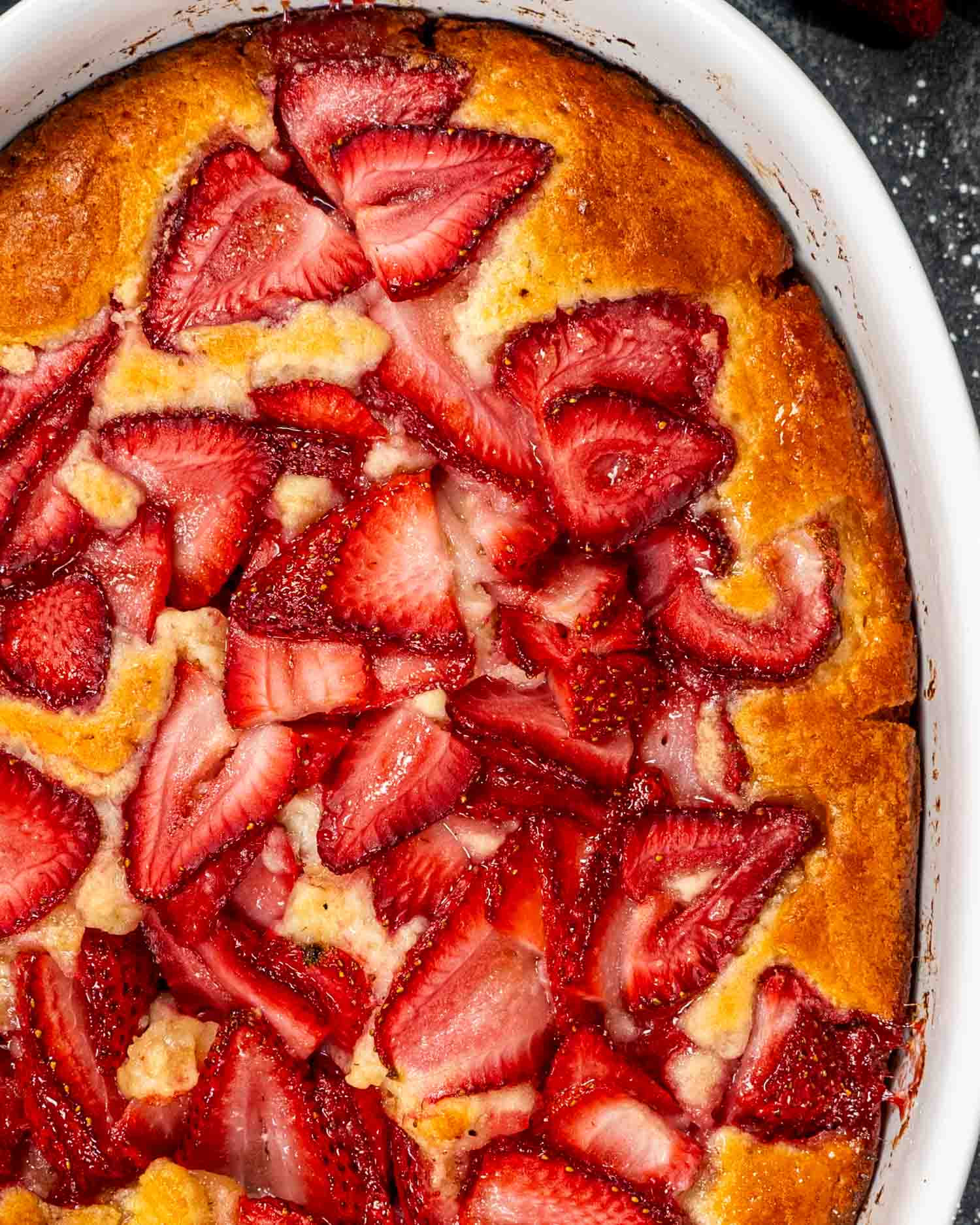 a freshly baked strawberry cobbler in a oval pan.