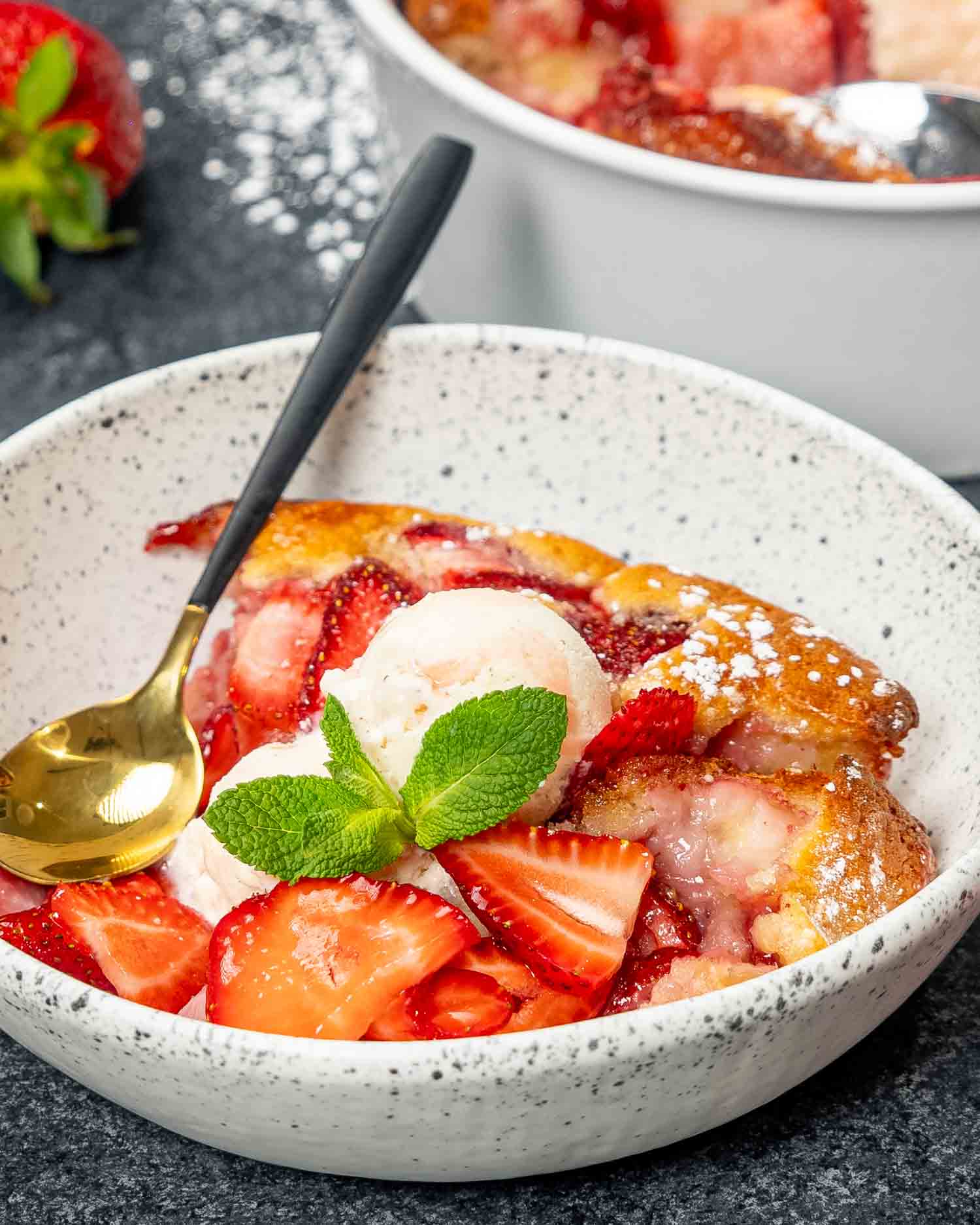 a serving of strawberry cobbler with a scoop of ice cream in a round bowl.