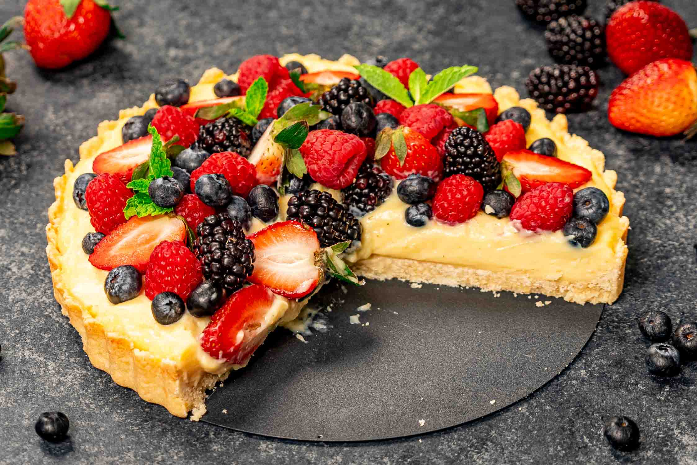 a gorgeous freshly made berry tart with a couple slices cut out of it.