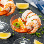 Cocktail glasses filled with shrimp cocktail, beautifully garnished with fresh lemon wedges and parsley on a table.