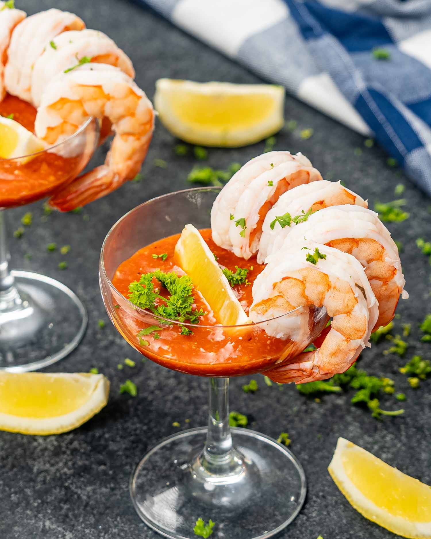 Cocktail glasses filled with shrimp cocktail, beautifully garnished with fresh lemon wedges and parsley on a table.