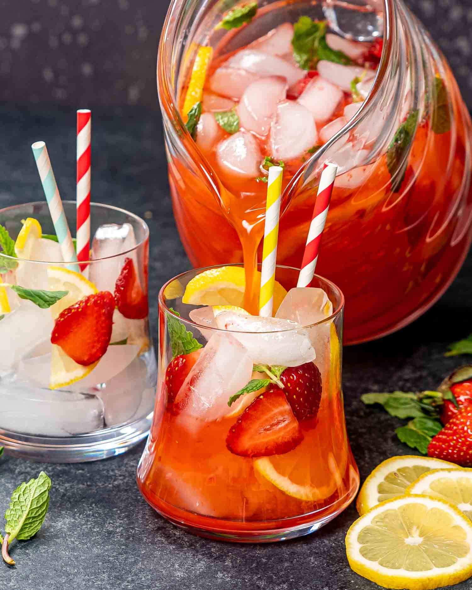 two glasses filled with strawberry lemonade garnished with lemon slices and strawberries.