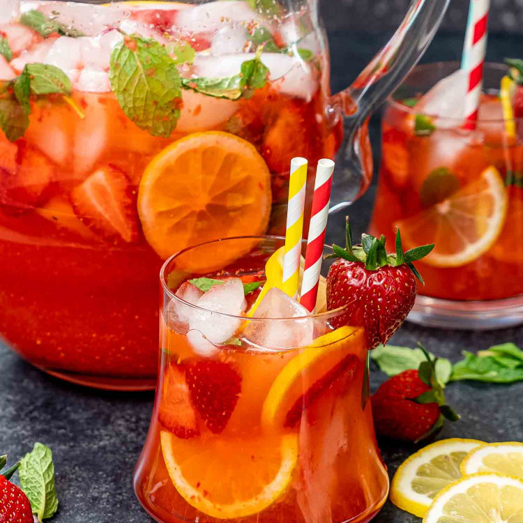 two glasses filled with strawberry lemonade garnished with lemon slices and strawberries.