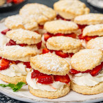 a few strawberry shortcakes on a white platter sprinkled with powdered sugar.