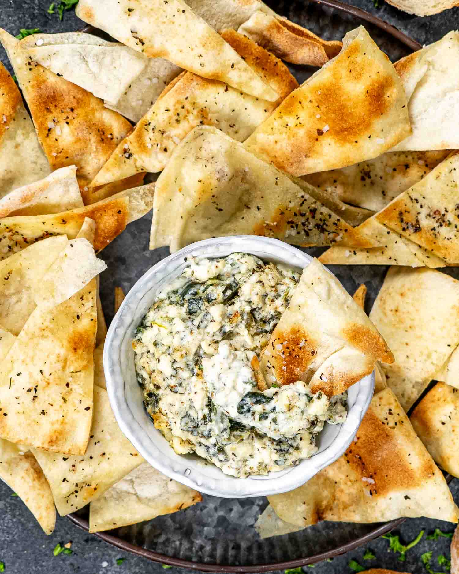 a small bowl with baked feta spinach dip with pita bread for dipping.