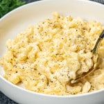 mac and cheese made in the instant pot in a white bowl garnished with salt and pepper.