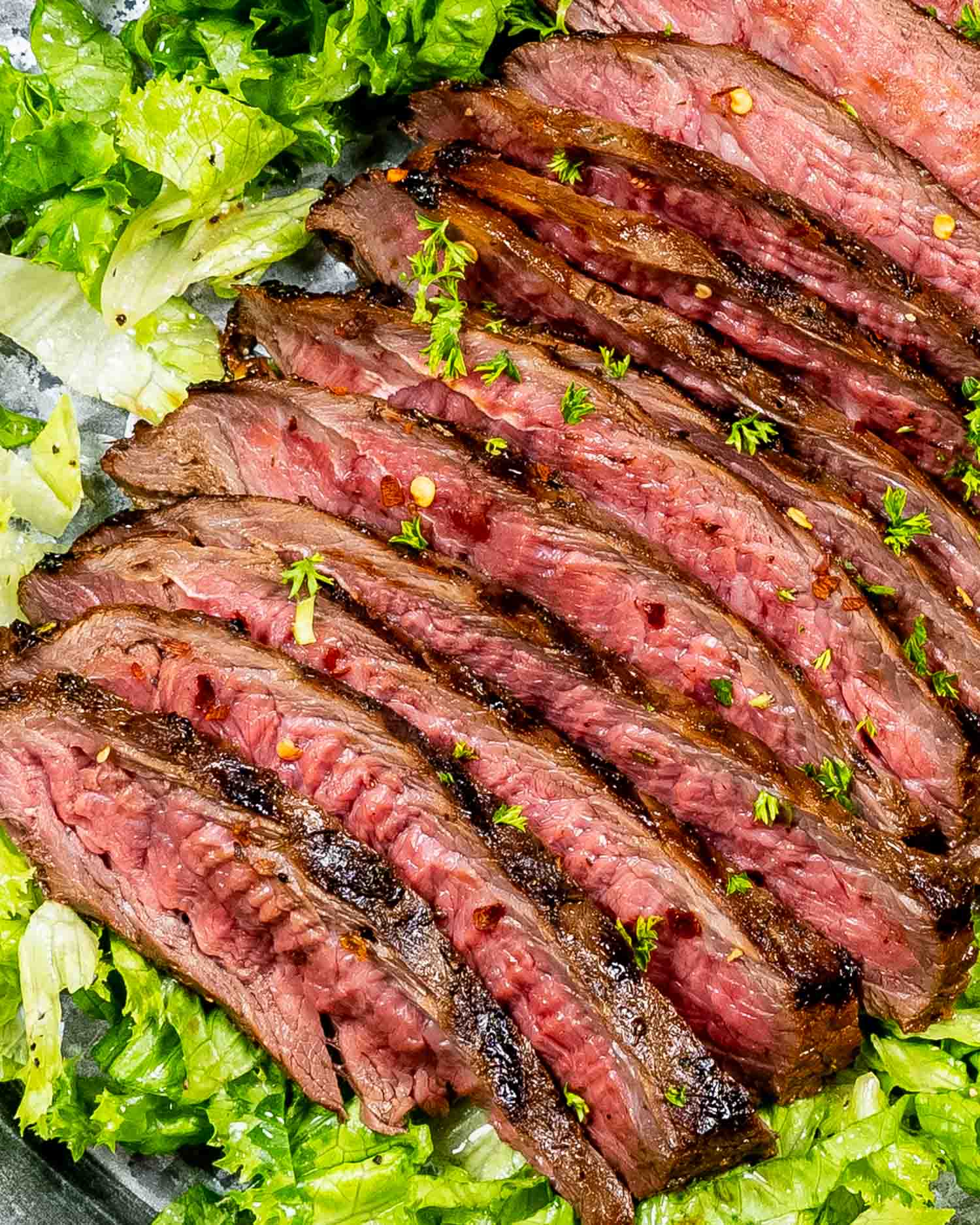 london broil all sliced up on a bed of lettuce.