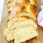 a gorgeous, freshly baked challah bread, half of it sliced on a cutting board.