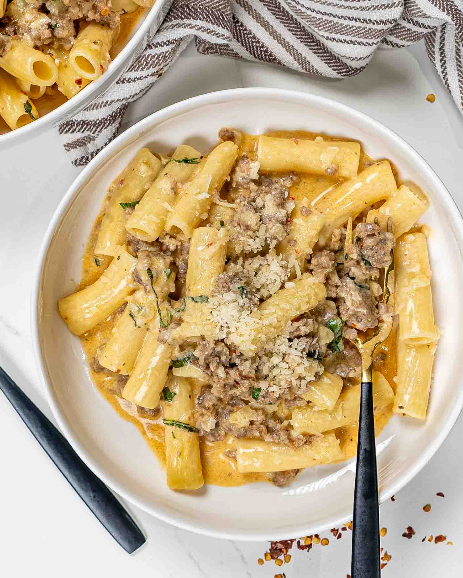 a serving of creamy italian sausage pasta in a white bowl.