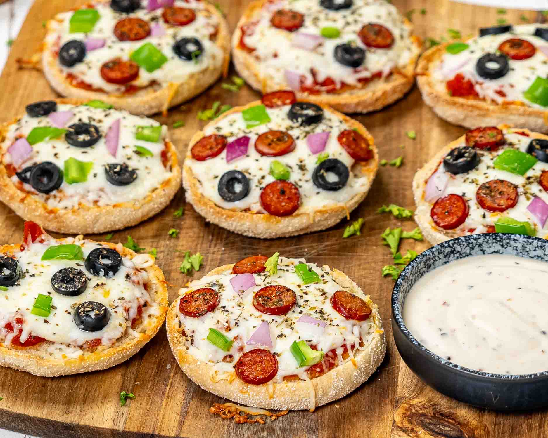 english muffin pizzas on a cutting board.