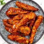 air fried honey bbq chicken tenders on a metal plate garnished with parsley.