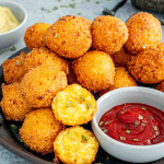 hush puppies on a plate with a little bowl with ketchup.