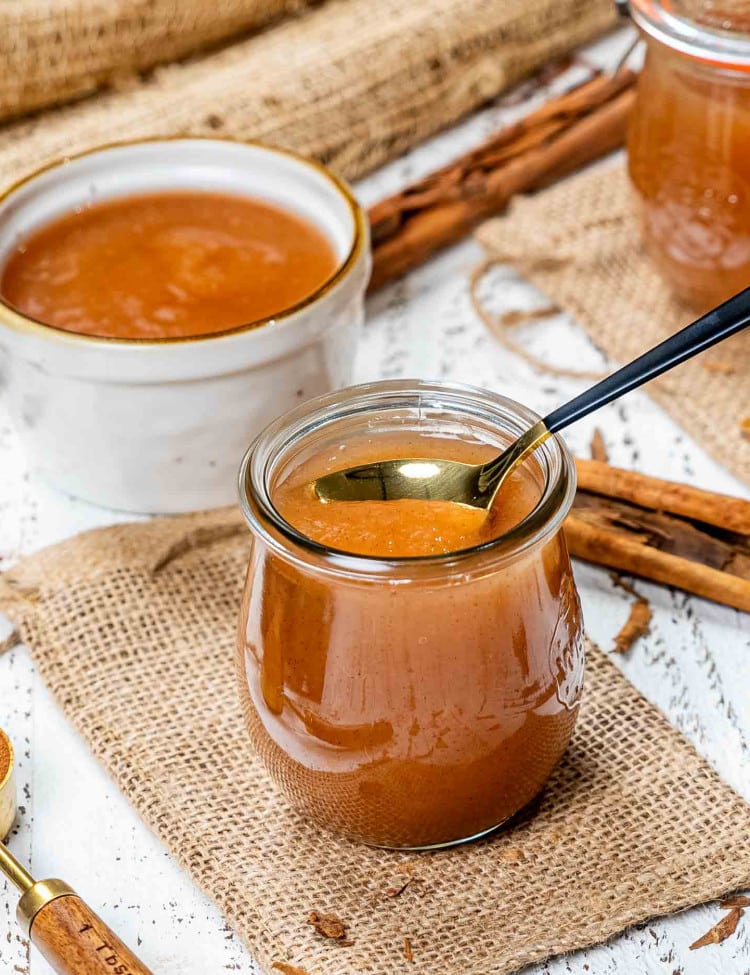 a tulip jar with applesauce in it made in the instant pot and a spoon inside the jar.