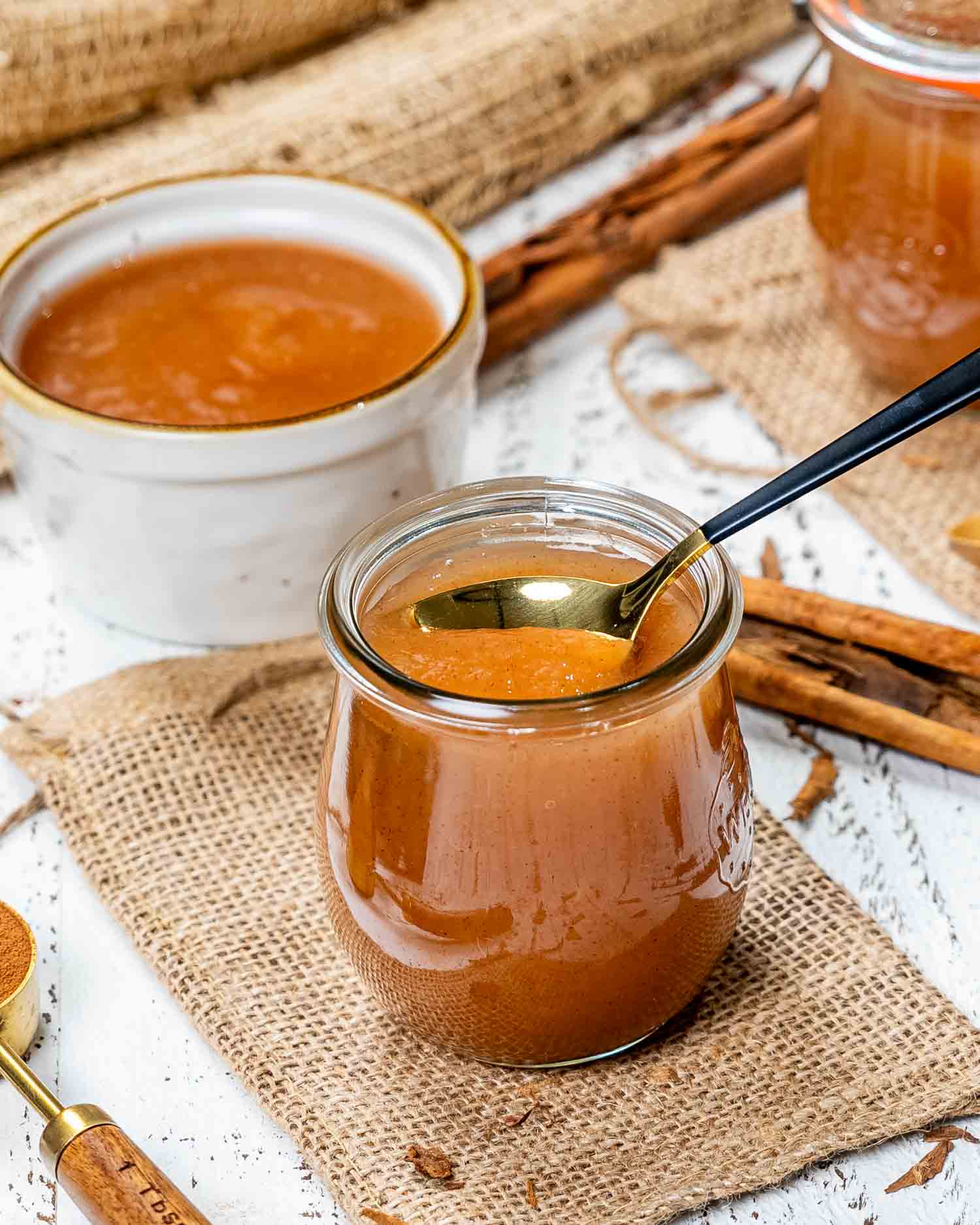 a tulip jar with applesauce in it made in the instant pot and a spoon inside the jar.