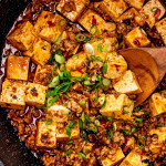 freshly made mapo tofu garnished with green onions in a skillet.