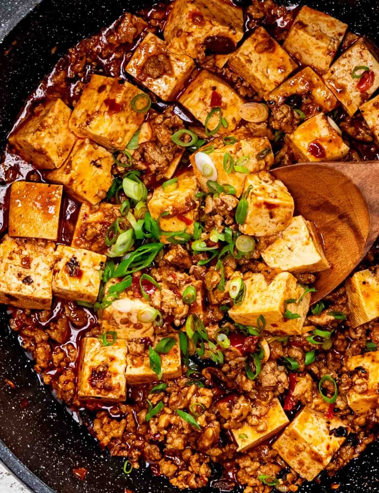 freshly made mapo tofu garnished with green onions in a skillet.