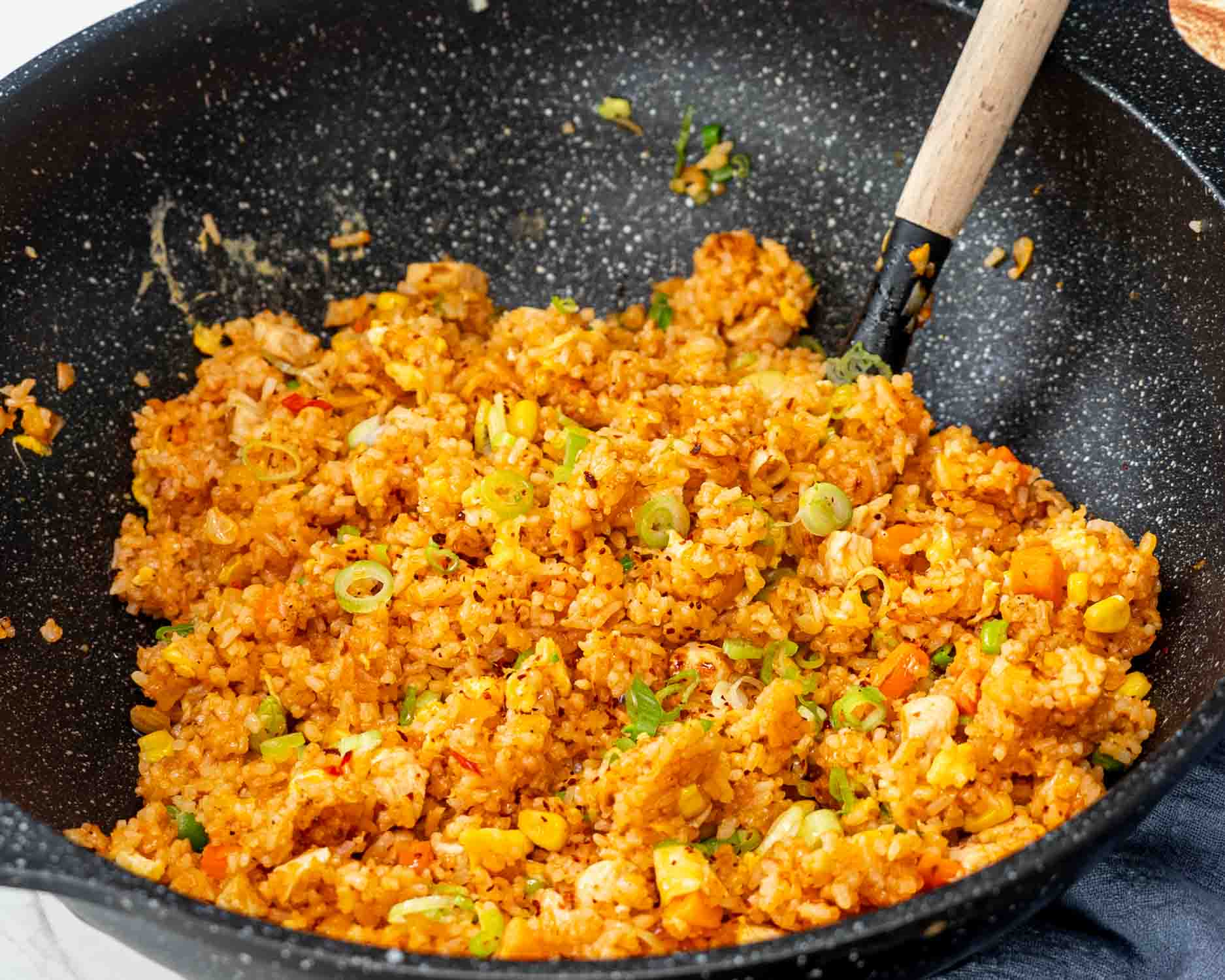 freshly made nasi goreng in a wok with a spatula in it.