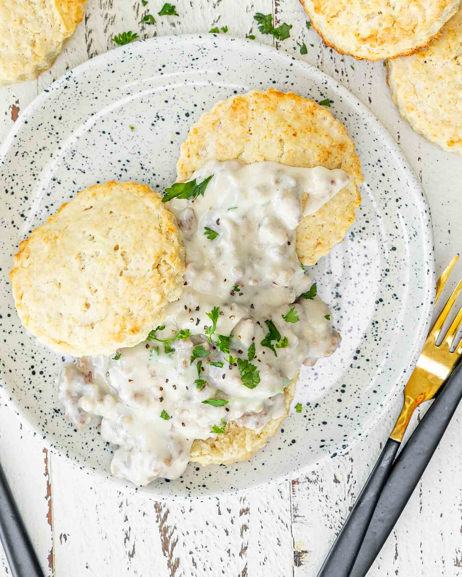 biscuits and gravy on a white little plate garnished with parsley.