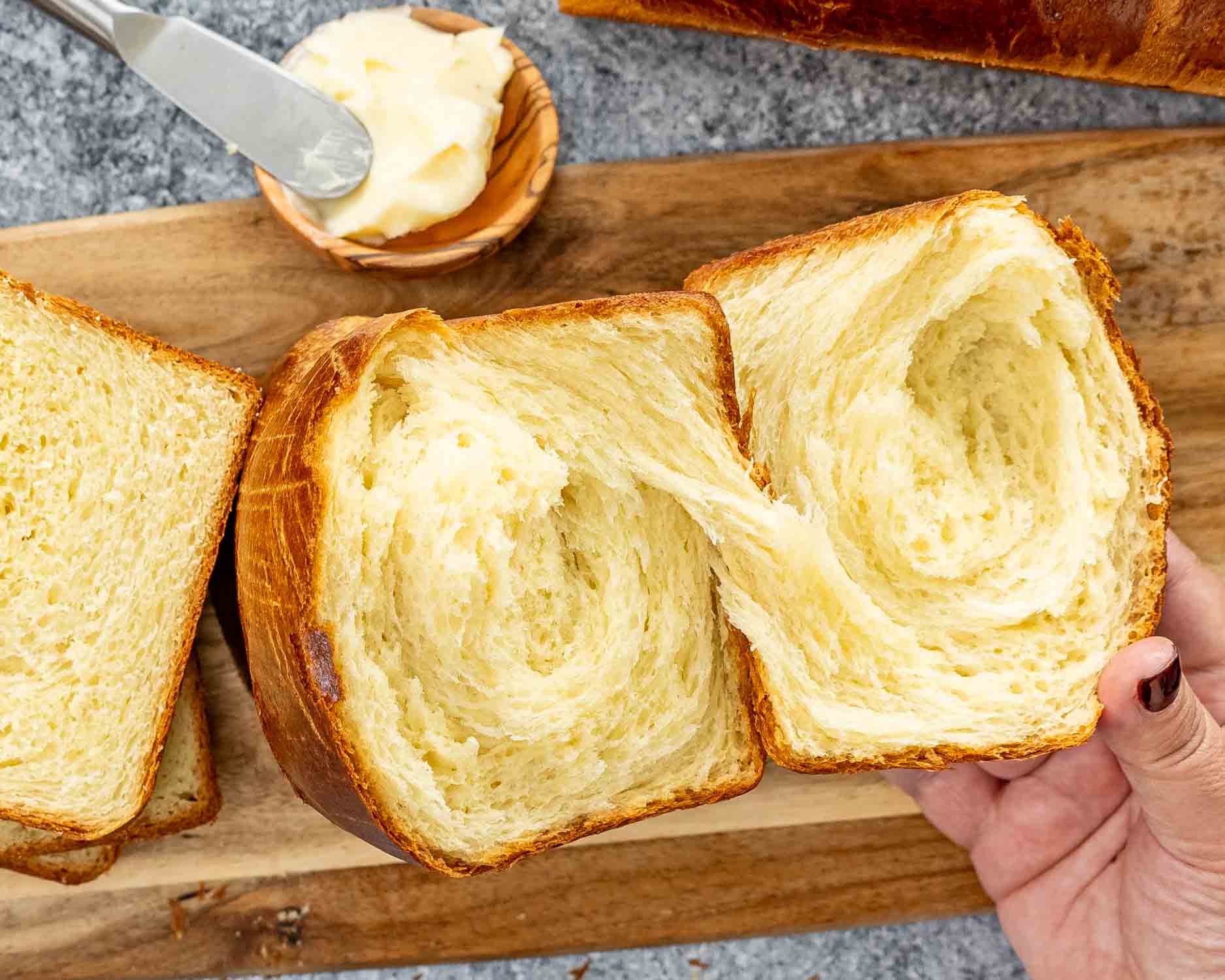 a brioche bread broken in half showing all the flakiness of the bread.