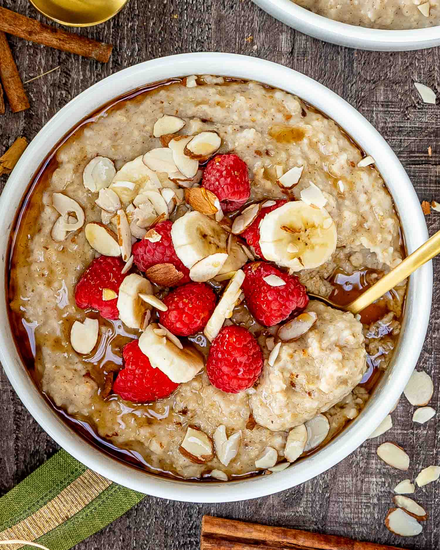 a big white bowl loaded with instant pot steel cut oats garnished with bananas, raspberries, and some sliced almonds.