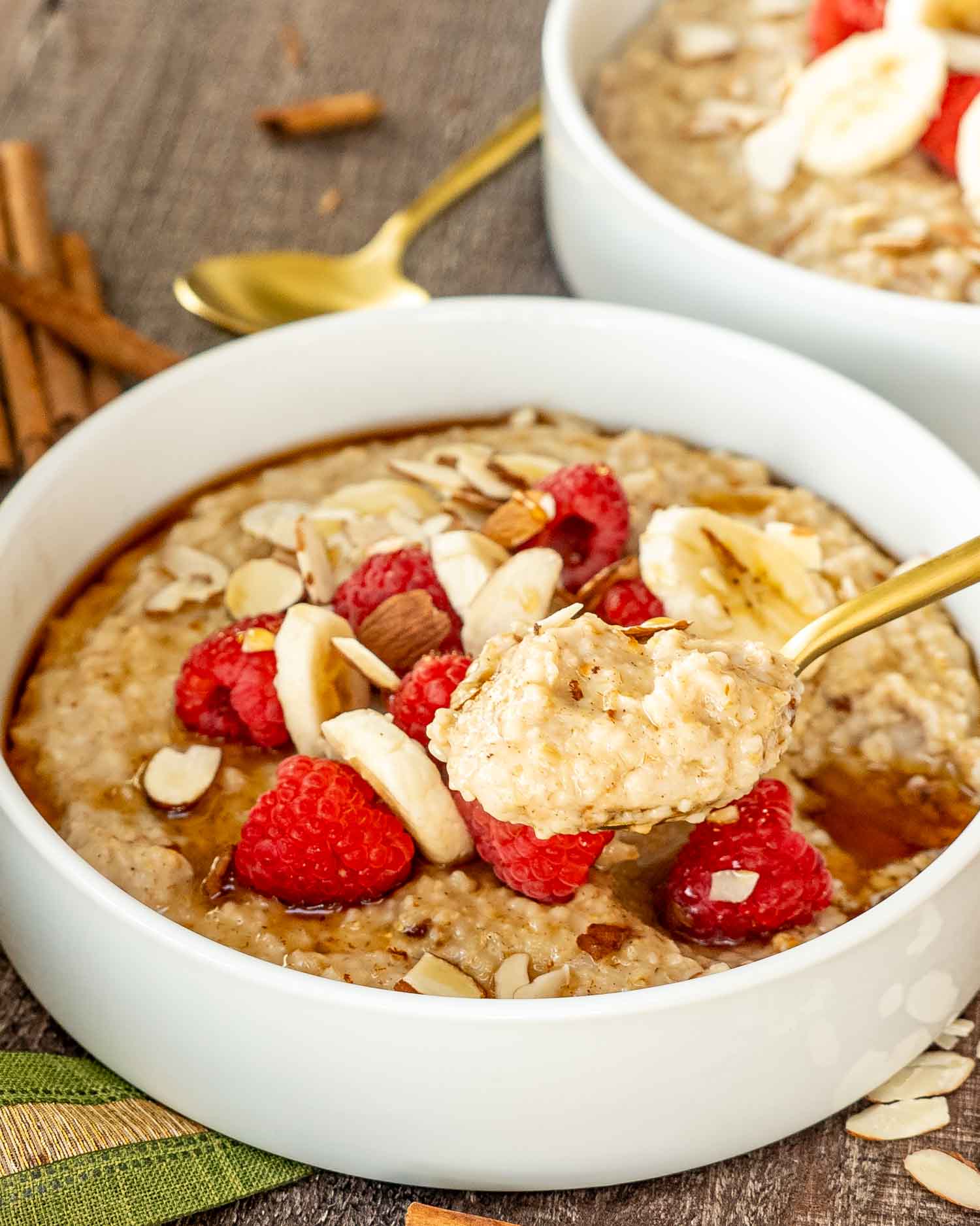 a big white bowl loaded with instant pot steel cut oats garnished with bananas, raspberries, and some sliced almonds.