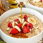 a big white bowl loaded with instant pot steel cut oats garnished with bananas, raspberries, and some sliced almonds.