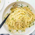 a serving of lemon pasta in a white bowl garnished with parsley and parmesan cheese.