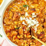 a big white bowl of mom's pork and beans topped with some chopped onion.
